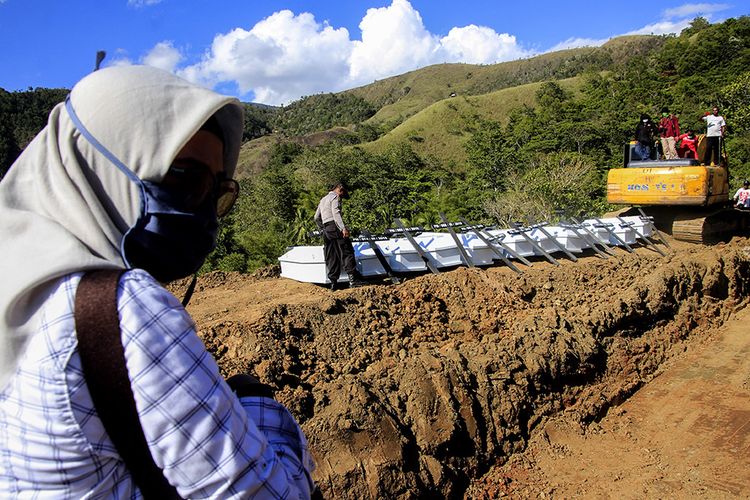 Personel kepolisian bersiap memasukkan peti berisi jenazah korban banjir bandang Sentani yang dikuburkan secara massal di Pemakaman Umum Kampung Harapan Sentani, Jayapura, Papua, Rabu (27/3/2019). Sebanyak 20 jenazah yang belum teridentifikasi dikuburkan secara massal.