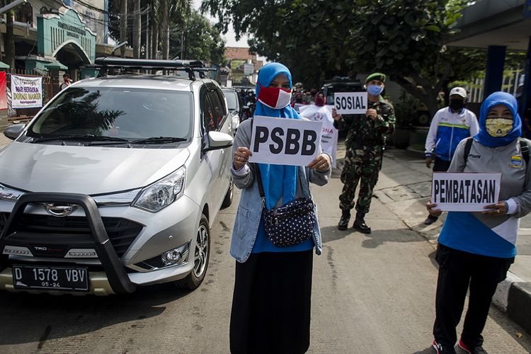 Massa yang tergabung dari ASN, warga, personel polisi dan TNI melakukan aksi kampanye pembatasan sosial berskala besar (PSBB) Kota Bandung di Alun Alun Ujungberung, Bandung, Jawa Barat, Senin (20/4/2020). Aksi tersebut guna mengedukasi dan sosialisasi kepada warga dan pedagang terkait kebijakan penerapan PSBB di Bandung Raya yang dimulai pada Rabu, 22 April 2020 sebagai bentuk memutus penyebaran Covid-19.