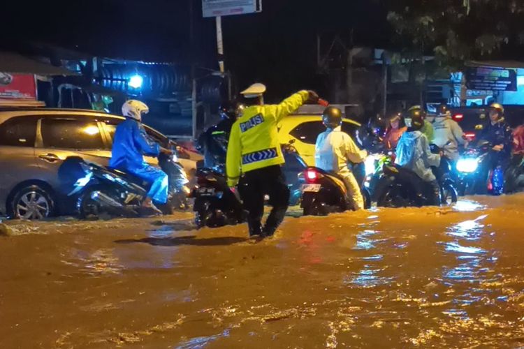 Pwtugas kepolisian tengah mengatur arus lalu lintas di Jalan Bhayangkara, yang tersendat lantaran terendam luapan sungai akibat hujan deras, selain itu beberapa Kecamatan di Kabupaten Bandung, Jawa Barat terendam banjir, Jumat (31/10/2025)