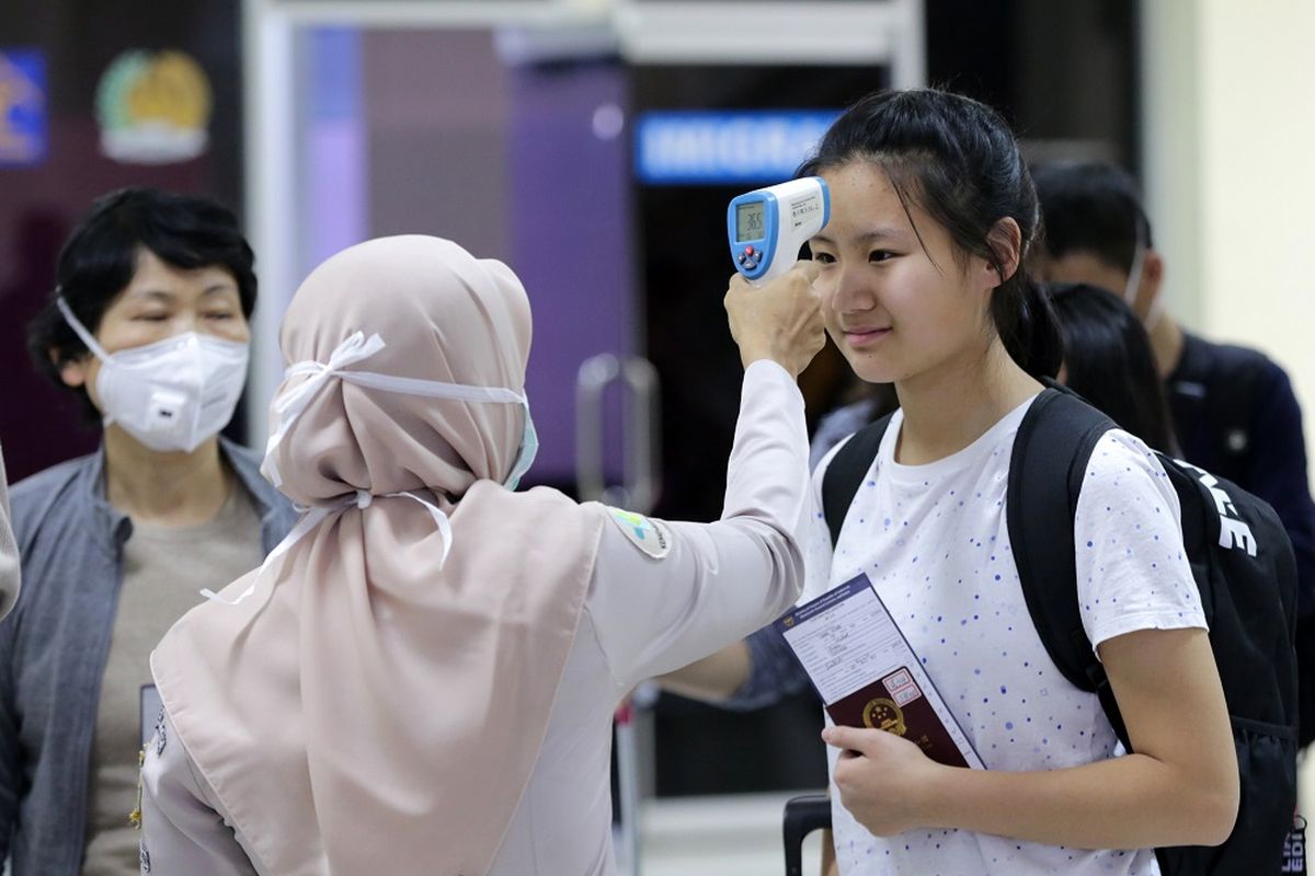 Petugas Kantor Kesehatan Pelabuhan (KKP) bandara Sultan Iskandar Muda (SIM) memeriksa penumpang yang baru tiba dari Malaysia dengan alat deteksi suhu tubuh (thermoscan) di terminal kedatangan bandara Internasional SIM, Aceh Besar, Aceh, Senin (27/1/2020). Pengamatan dan pemeriksaan menggunakan alat pendeteksian suhu tubuh terhadap para penumpang pesawat luar negeri di terminal kedatangan jalur internasional guna mengantisipasi penyebaran Virus Corona. ANTARA FOTO/Irwansyah Putra/ama.