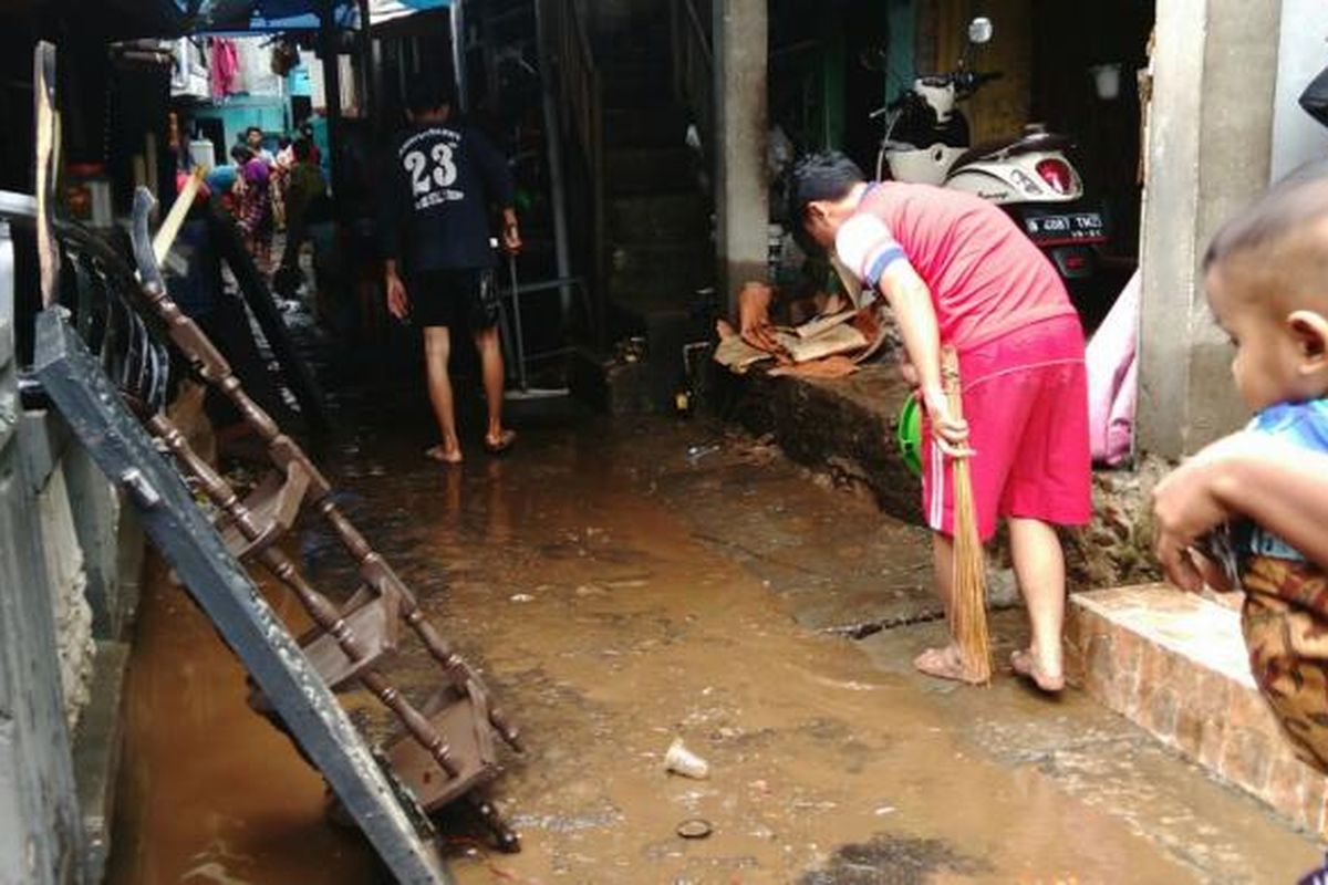 Warga Kebon Pala Tanah Rendah di Kampung Melayu, Jatinegara, Jakarta Timur membersihkan pekarangan rumah pasca banjir. Kamis (16/2/2017)