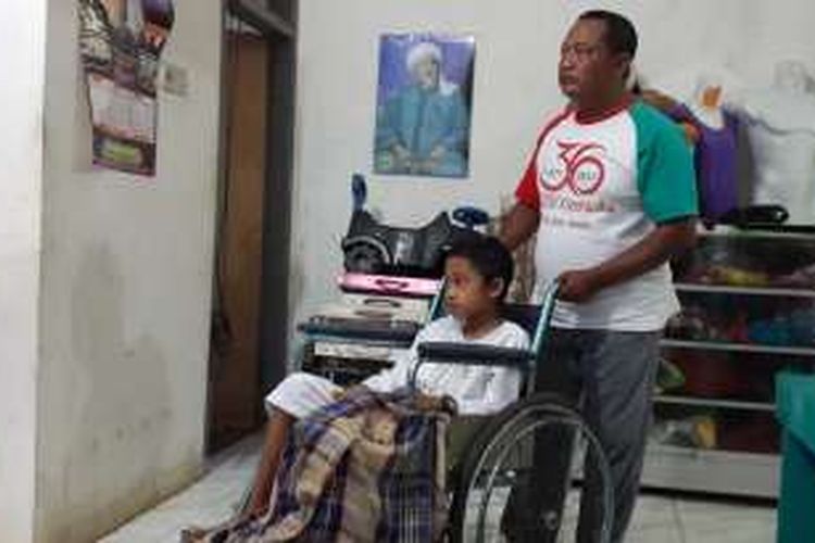 Setiyo Aldi, kakinya yang lumpuh akibat jatuh dan dioperasi saat dibawa melalui kursi roda oleh ayahnya, Kamis (10/11/2016)