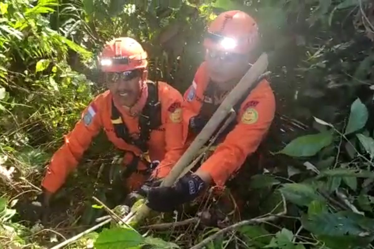 Dua petugas Basarnas Bali saat berupaya mengevakuasi seorang pelajar berinisial CS (18), asal Papua di sebuah jurang sedalam 40 meter di di Desa Besang Kawan Semarapura Kaja, Klungkung, Bali pada Rabu (20/7/2022). /Dok.Humas Basarnas Bali
