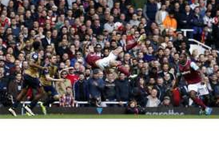Striker West Ham United, Andy Carroll (tengah), melepaskan tendangan salto dalam pertandingan Premier League melawan Arsenal di The Boleyn Ground, Upton Park, Sabtu (9/4/2016).