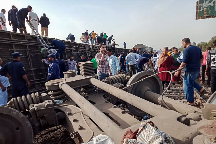 Warga berkumpul di lokasi kecelakaan kereta Mesir di Toukh, provinsi Qalyubiya, pada Minggu (18/4/2021). Kecelakaan ini berawal dari 8 gerbong yang anjlok setelah berangkat dari Kairo, dan membuat 97 orang terluka.