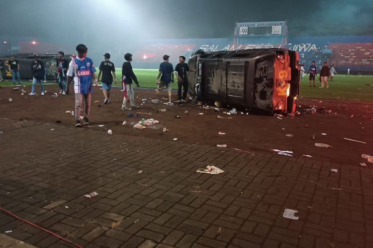 Mobil K-9 dibalik oleh supporter Aremania dalam kericuhan yang terjadi di Stadion Kanjuruhan, Sabtu (1/10/2022).