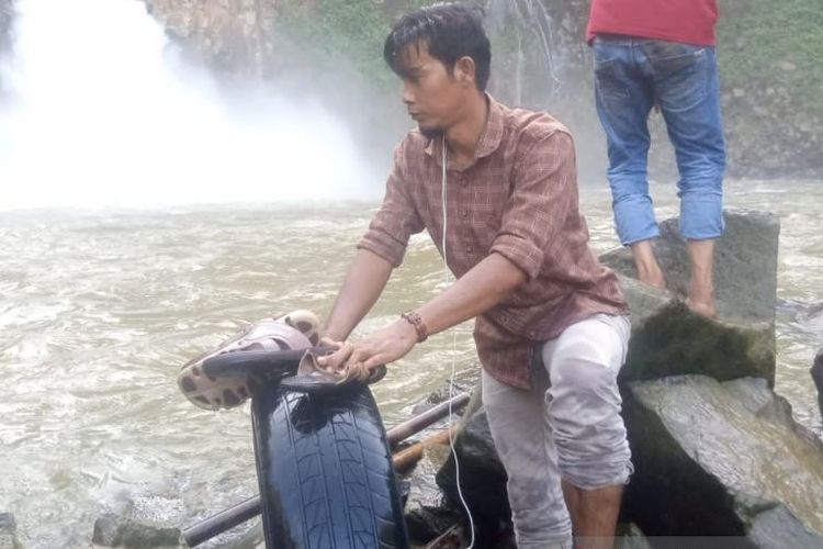 Warga memperlihatkan bagian ban mobil dan sandal perempuan di dalam Air Terjun Kedabuhan, di Desa Jontor, Kecamatan Penanggalan, Kota Subulussalam, Aceh, Senin (13/12/2021).
