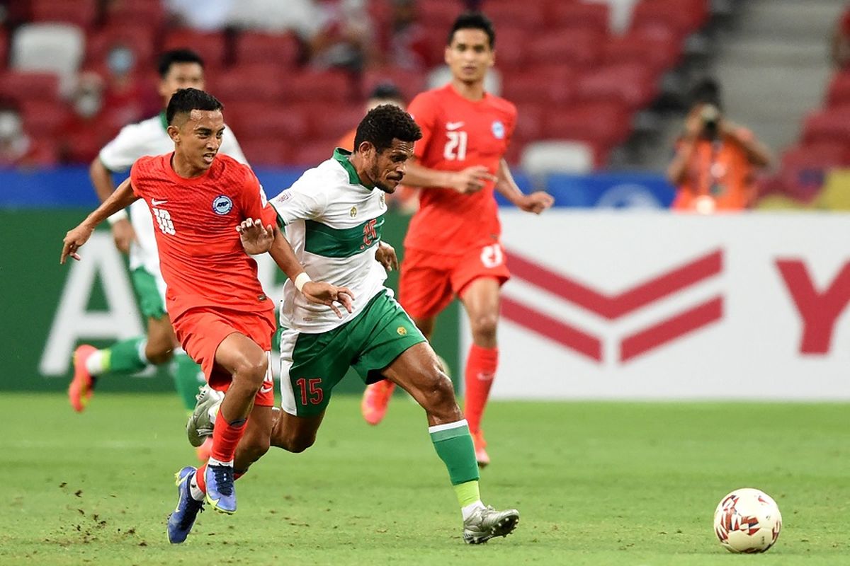 Pemain Singapura Faris Ramli (kiri) berebut bola dengan pemain Indonesia Ricky Richardo Kambuaya pada pertandingan leg pertama semifinal AFF Suzuki Cup 2020 antara Singapura vs Indonesia di National Stadium, Singapura, pada 22 Desember 2021.