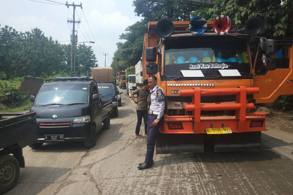 Petugas Dishub Kab. Tangerang menerapkan buka-tutup arus di Jalan Raya Parung untuk menghindari penumpukan kendaraan, Rabu (9/1/2019).