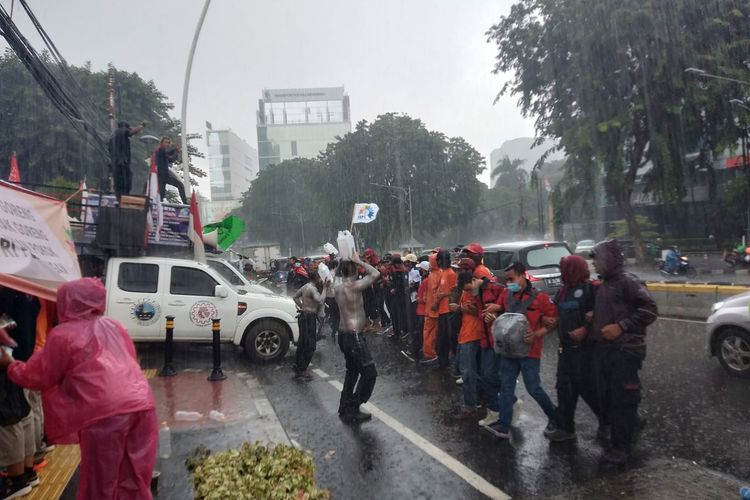 Massa buruh bersama petani tetap bertahan unjuk rasa di depan Kantor Kementerian Perdagangan, Jakarta Pusat, Selasa (22/3/2022), meski hujan deras mengguyur. Massa aksi menuntut pemerintah turunkan harga minyak goreng.
