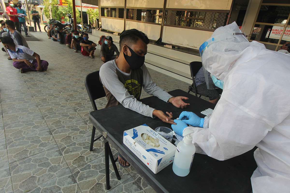 Foto dirilis Kamis (25/6/2020), memperlihatkan petugas melakukan tes cepat (Rapid Test) COVID-19 kepada warga yang terjaring razia pembatasan aktivitas malam hari di Polres Pelabuhan Tanjung Perak Surabaya, Jawa Timur. Sekitar 4.312 aparat gabungan diterjunkan guna mengamankan pelaksanaan PSBB di Kota Surabaya, Kabupaten Gresik, dan Kabupaten Sidoarjo, yang tiga kawasan itu lebih dikenal dengan Surabaya Raya.