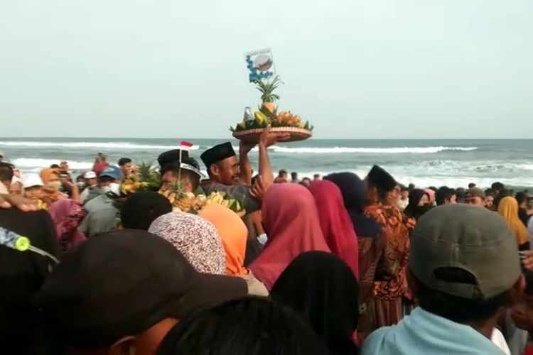 Ribuan warga sedang bersiap-siap memperebutkan tumpeng yang dipegang oleh sesepuh desa pada kegiatan sedekah laut yang digelar pada Minggu (31/7/2022)