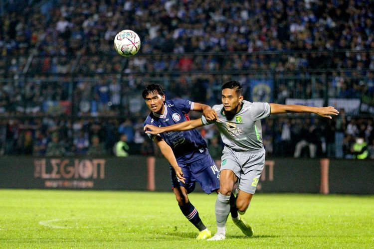 Pemain Arema FC Jayus Hariono berebut bola dengan Persebaya Surabaya Rizky Ridho saat pertandingan pekan ke-11 Liga 1 2022-2023 yang berakhir dengan skor 2-3 di Stadion Kanjuruhan Kepanjen, Kabupaten Malang, Sabtu (1/10/2022) malam.