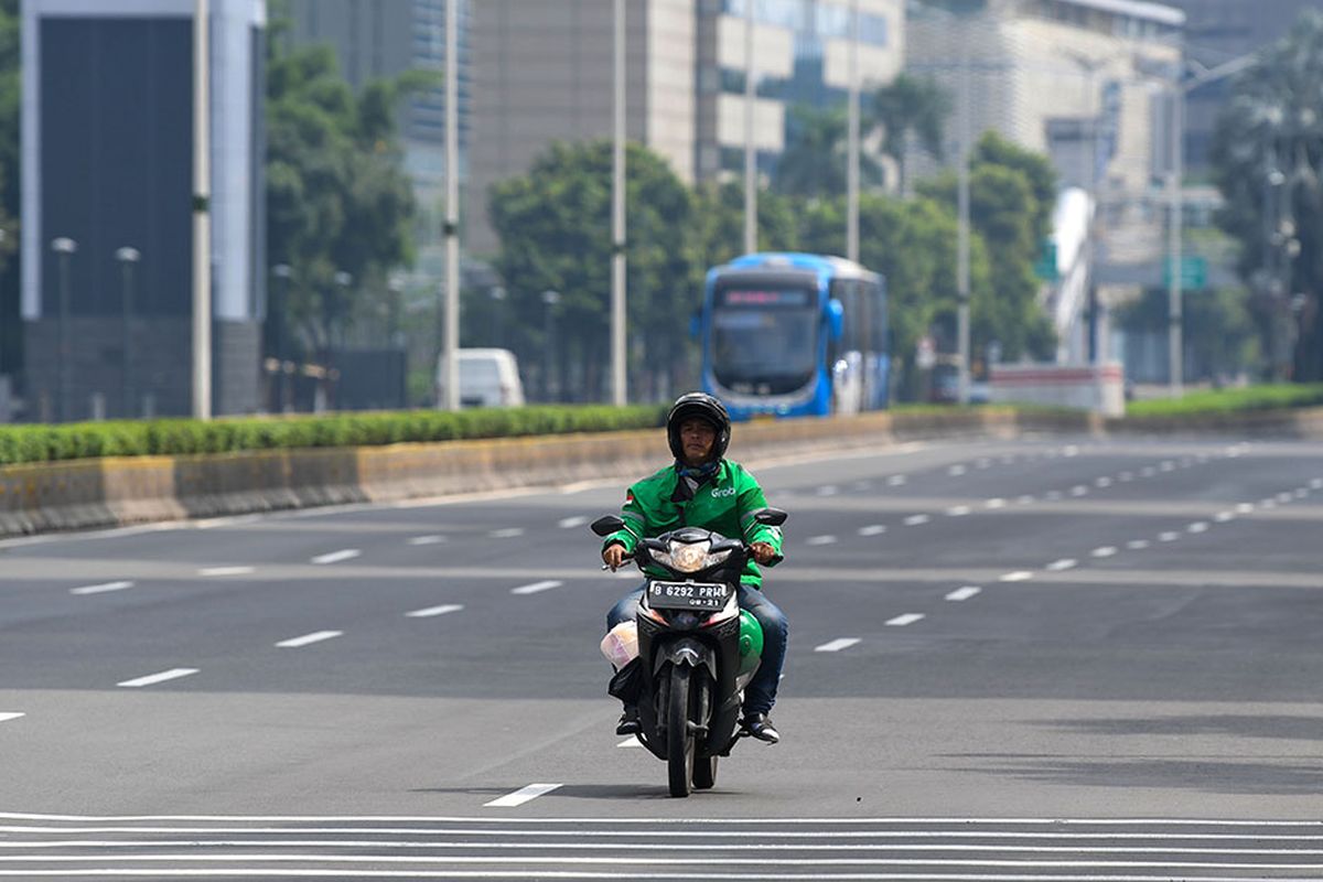 Pengendara ojek daring melintasi jalan MH Thamrin, Jakarta, Minggu (29/3/2020). Pemprov DKI Jakarta melakukan pembatasan aktivitas di Ibu Kota dengan memperpanjang masa tanggap darurat COVID-19 hingga 19 April 2020 sehubungan dengan meluasnya pandemi COVID-19.