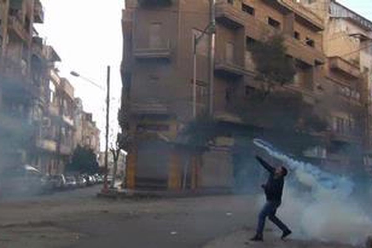 Seorang pemrotes di Kota Homs di Suriah tengah melemparkan sebuah bom gas air mata ke pasukan keamanan pada 27 Desember 2011.