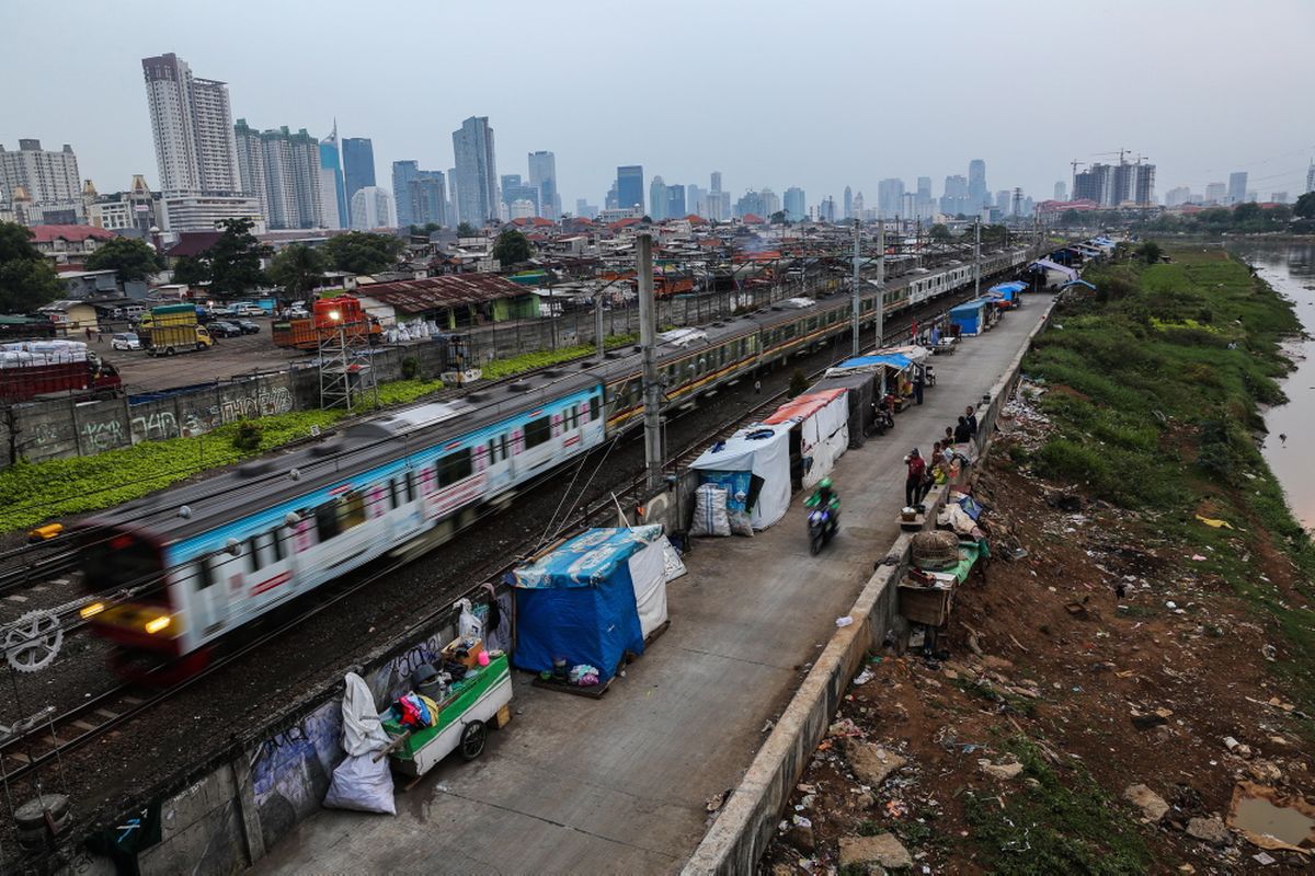 Kereta listrik (KRL) melintas di samping deretan bangunan liar di sepanjang tepi Sungai Ciliwung, Jalan Tenaga Listrik, Tanah Abang, Jakarta Pusat, Sabtu (30/9/2017). Gubuk liar kembali berdiri di sepanjang Sungai Ciliwung akibat kurangnya pengawasan dari Pemprov DKI Jakarta.