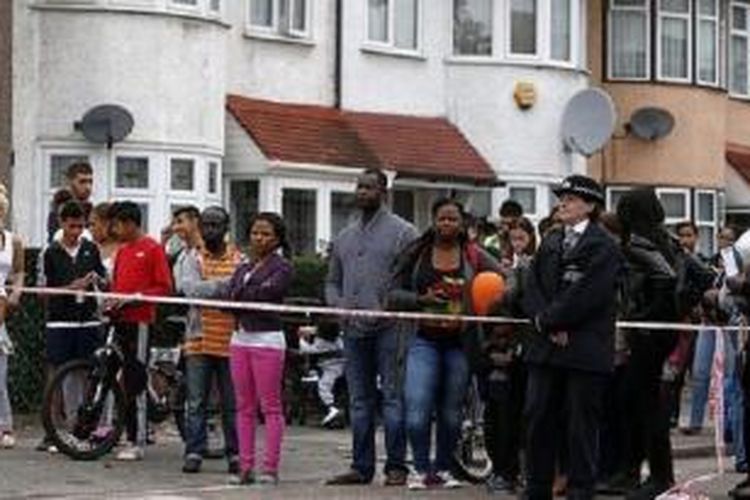 Sejumlah warga London menonton penyelidikan polisi setelah seorang perempuan tua dipenggal oleh seorang pria muda di sebuah taman di kota itu, Kamis (4/9/2014). 

