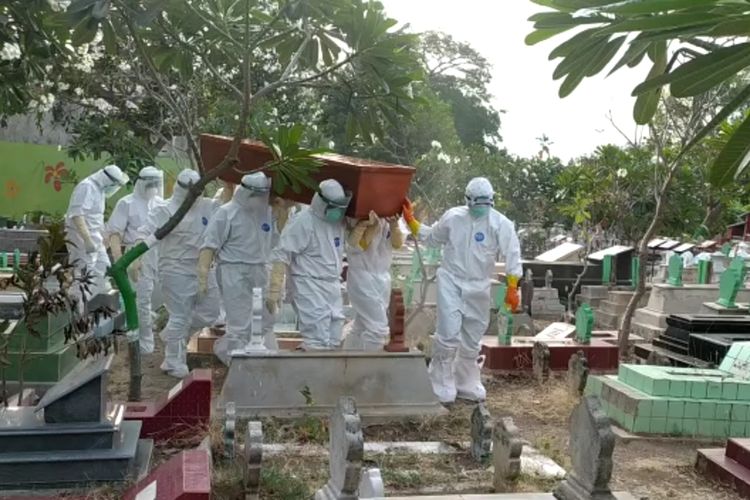 MAKAMKAN—Atong bersama timnya mengubur salah satu jenazah kasus covid-19 di Kota Madiun