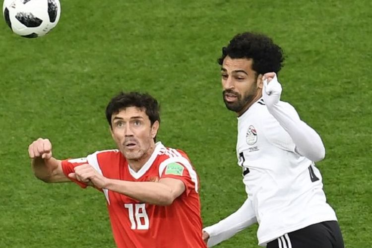 Yuri Zhirkov dan Mohamed Salah mencoba menyundul bola pada pertandingan Rusia vs Mesir di St. Petersburg, 19 Juni 2018. 