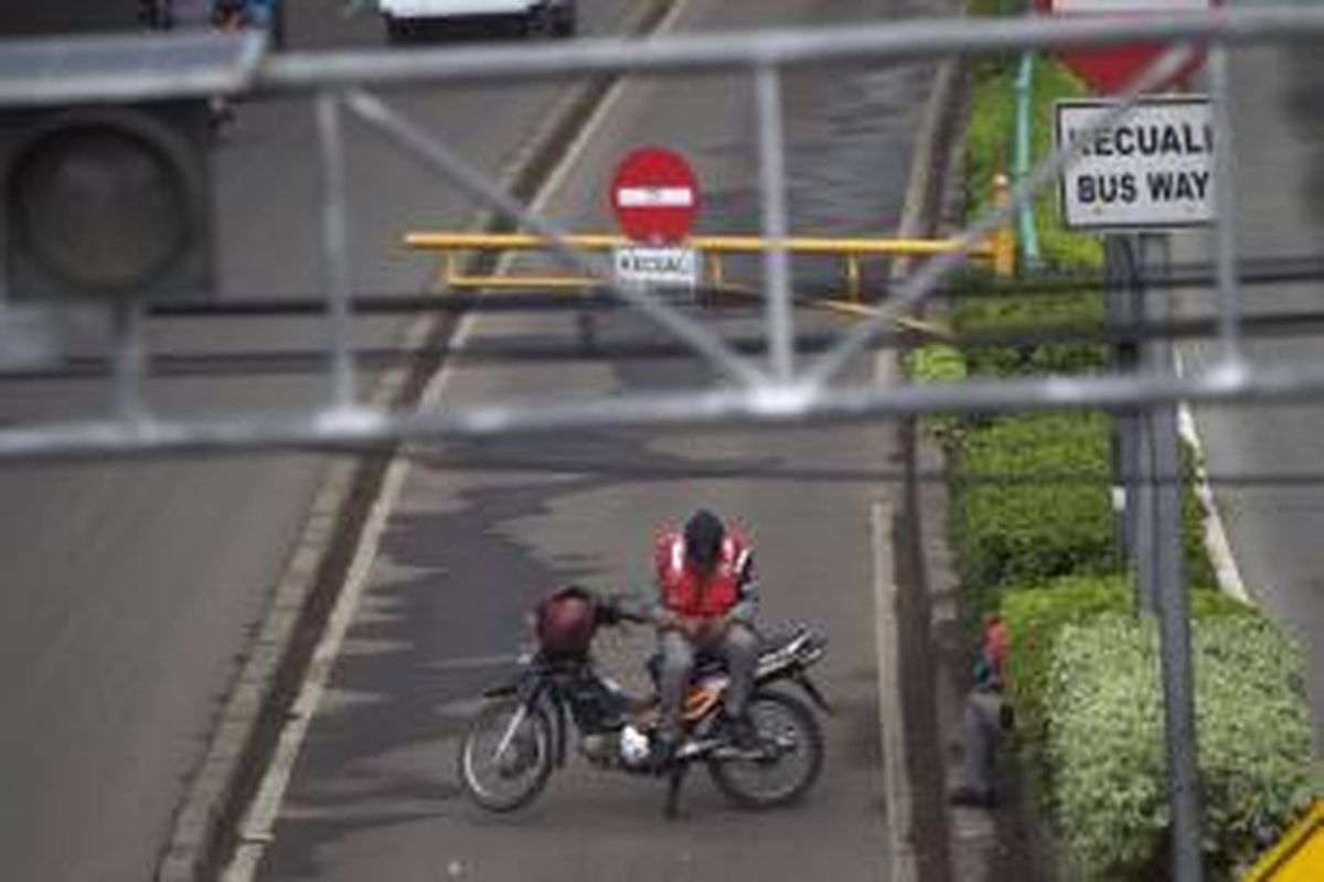 Petugas membuka telepon genggam di atas sepeda motor yang digunakan untuk menutup jalur bus Transjakarta di Jalan Otto Iskandardinata, Jakarta Timur, Rabu (29/5/2013). Jalur tersebut ditutup karena ada bus transjakarta yang mogok.