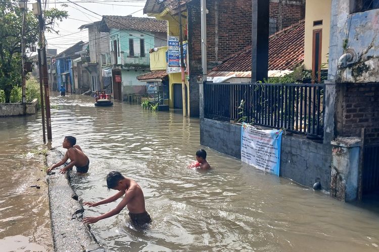 Warga di Kampung Bojongasih, Desa Dayeuhkolot, Kabupaten Bandung, Jawa Barat, beraktifitas mengangkuta gas di yengah banjir luapan sungai Citarum yang belum surut, Senin (31/11/2025)