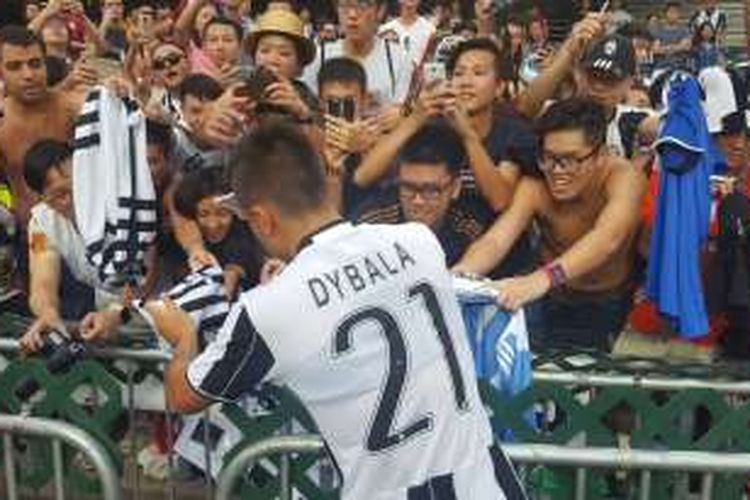 Striker Juventus, Paulo Dybala, memberikan tanda tangan kepada penggemar setelah partai uji coba kontra South China di Hongkong Stadium, Sabtu (30/7/2016).