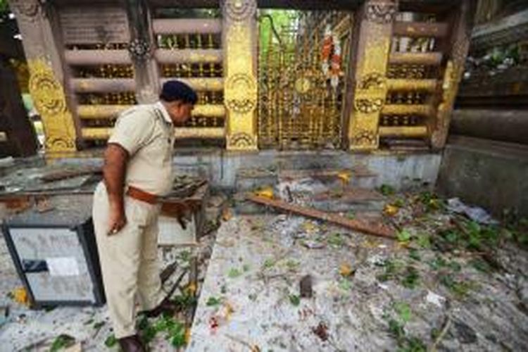 Seorang anggota kepolisian India tengah melihat puing-puing yang disebabkan ledakan sekitar 10 buah bom di tempat paling suci bagi umat Buddha, Bodh Gaya.
