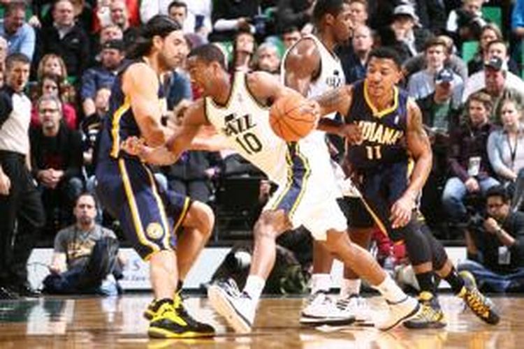 Pebasket Utah Jazz, Alec Burks (putih) mencoba melewati pomain Indiana Pacers, Luis Scola (kiri) dan  Orlando Johnson (11), pada laga lanjutan kompetisi NBA di EnergySolutions Arena, Rabu (04/12/2013).