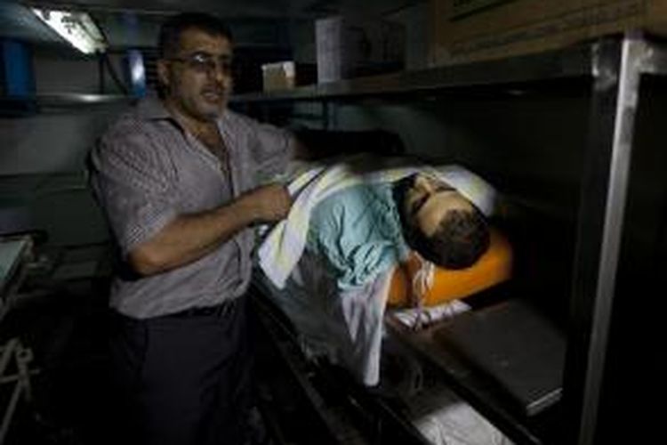 Seorang petugas rumah sakit Palestina menunjukkan jasad seorang pria yang menjadi salah satu korban tewas serbuan pasukan polisi perbatasan Israel ke kamp pengungsi Qalandiya, Tepi Barat.