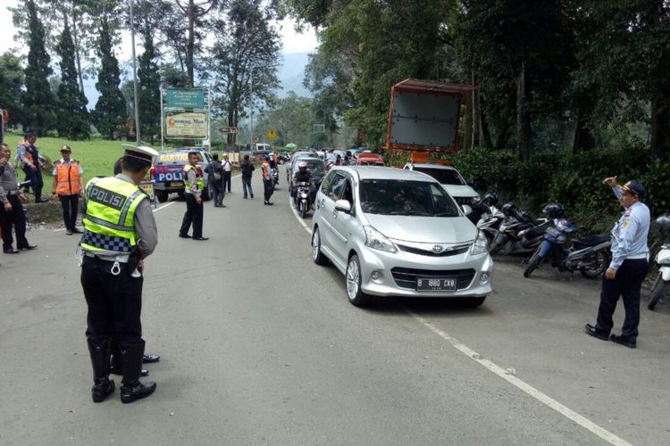 Petugas kepolisian sedang mengatur arus lalu lintas di kawasan Gunung Mas Puncak dalam penerapan uji coba dibukanya kembali jalur Puncak setelah sempat ditutup paska peristiwa bencana longsor beberapa waktu lalu, Senin (19/2/2018).