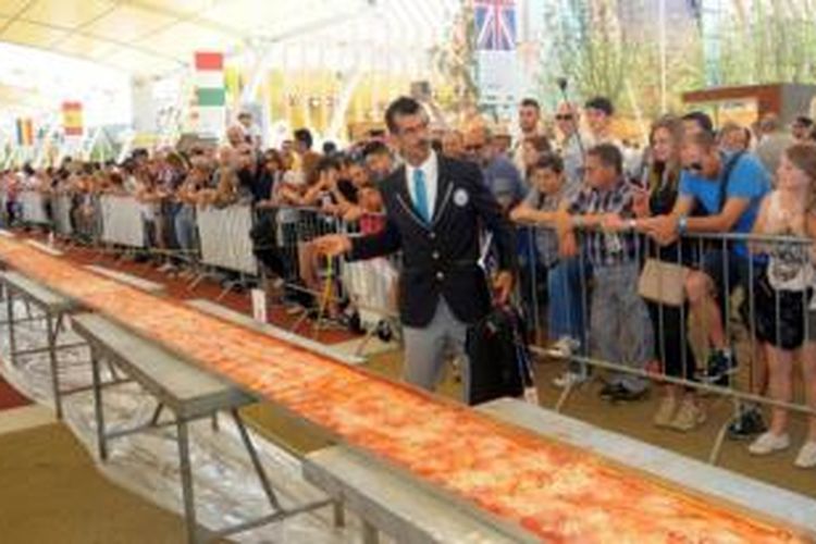 Juri dari Guinness World Records Lorenzo Veltri memeriksa panjang sebuah piza margherita yang dibuat di Expo 2015 yang digelar di kota Rho, dekat Milan, Italia, Sabtu (20/6/2015). 
