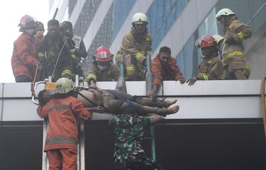 Petugas mengevakuasi korban kebakaran yang terjadi di Gedung Cyber I, Mampang, Jakarta, Kamis (2/12/2021). Dinas Penanggulangan Kebakaran dan Penyelamatan Jakarta mengerahkan 100 personel beserta 22 unit mobil pemadam ke lokasi. Api berhasil dipadamkan dalam waktu 30 menit.