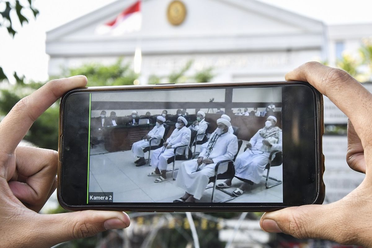 Jurnalis mengamati layar telepon pintar yang menampilkan sidang yang dihadiri Muhammad Rizieq Shihab di Pengadilan Negeri Jakarta Timur, Kamis (27/5/2021). Majelis Hakim menjatuhkan pidana denda Rp20 juta kepadaMuhammad Rizieq Shihab subsider lima bulan penjara atas kasus kerumunan massa di Megamendung, Bogor. ANTARA FOTO/ Fakhri Hermansyah/aww.