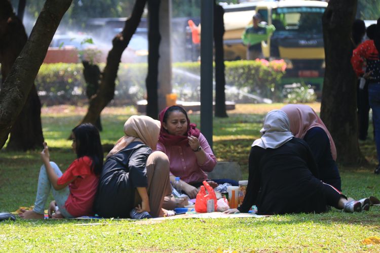 Nampak ibu-ibu bersama anaknya sedang duduk di Taman Kota di DKI Jakarta