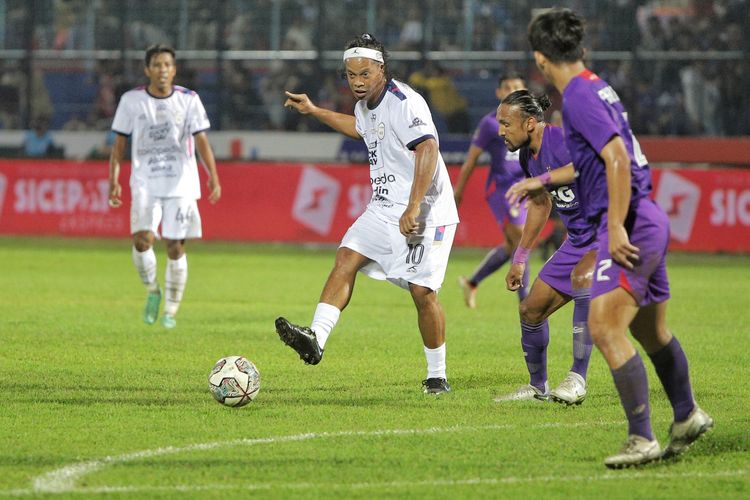 Mantan pesepak bola dunia asal Brazil Ronaldinho (tengah) dihadang pesepak bola Persik Kediri Rohit Chand (kedua kanan) saat pertandingan Trofeo Ronaldinho di Stadion Kanjuruhan, Malang, Jawa Timur, Minggu (26/6/2022). Terkini, putra Ronaldinho yang berusia 17 tahun, Joao Mendes, dikabarkan bakal bergabung dengan FC Barcelona. ANTARA FOTO/Rizal Hanafi/Ds/aww.