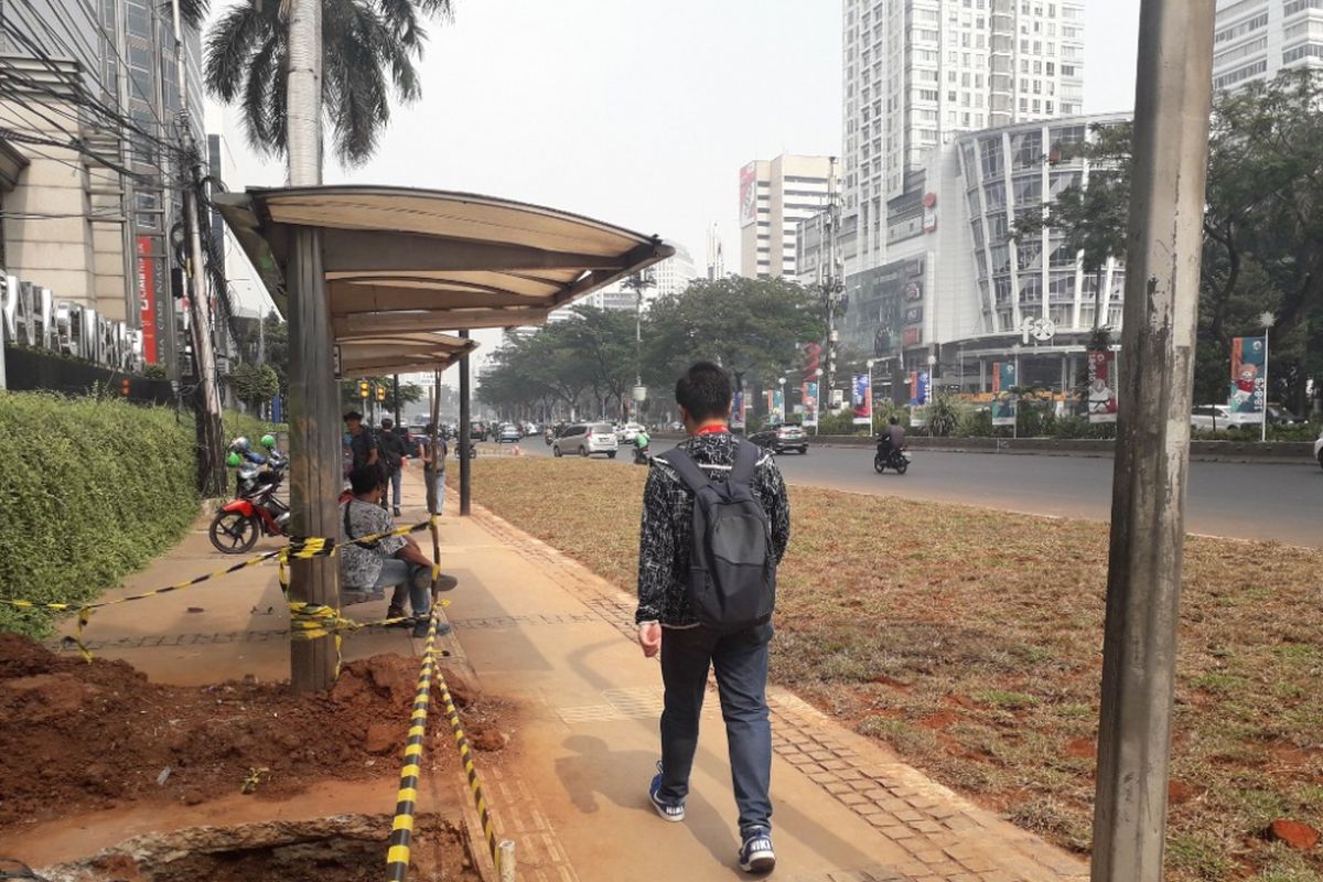 Halte bus di depan Gedung Graha CIMB Niaga, Jalan Jenderal Sudirman, yang aksesnya terhalang area rerumputan, Selasa (24/7/2018).