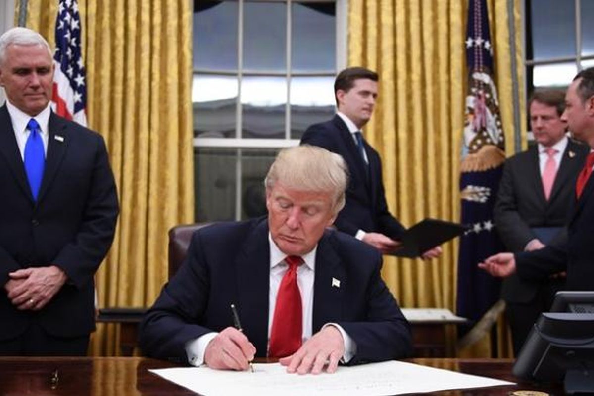 Presiden AS Donald Trump menandatangani sejumlah dokumen perintah eksekutifnya di Ruang Oval, Gedung Putih, disaksikan wakil presiden Mike Pence.