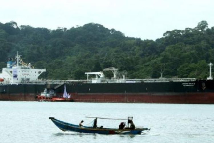 Perahu nelayan melintas di sekitar kapal tanker bermuatan bahan bakar yang menunggu proses bongkar muat di perairan selatan Pulau Nusakambangan, Cilacap, Jawa Tengah, pertengahan Mei. Wilayah perairan tersebut beberapa kali tercemar rembesan minyak dari proses bongkar muat minyak mentah menuju kilang-kilang PT Pertamina Refinery Unit IV Cilacap.