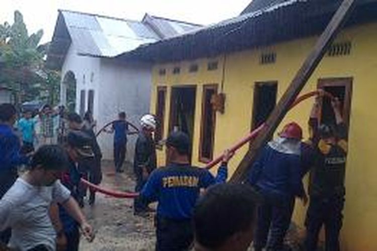 Sejumlah petugas pemadam kebakaran kota Kendari, berupaya memadamkan api yang telah menghanguskan satu rumah di Kendari. Meski saat kebakaran berlangsung hujan deras mengguyur kota Kendari.