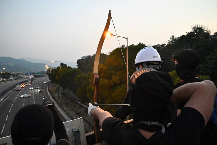 Seorang demonstran menggunakan panah untuk mengarahkan mobil yang melewati Jalan Raya Tolo, di luar Chinese University of Hong Kong pada 13 November 2019.