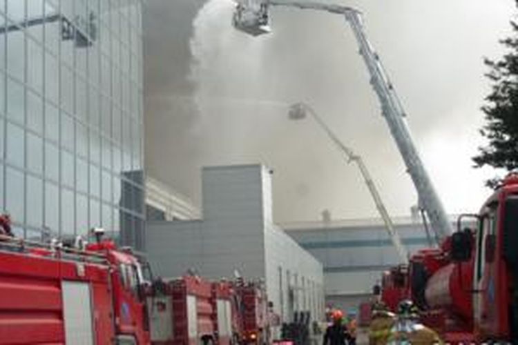 Petugas pemadam kebakaran sedang berusaha memadamkan api yang melanda sebuah pabrik di Korea Selatan yang memproduksi papan sirkuit ponsel pintar Samsung Galaxy S5