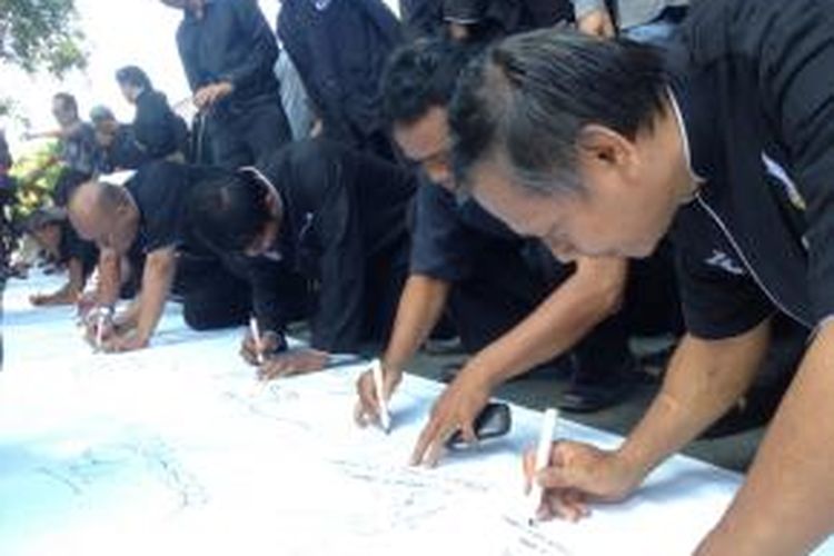 Warga Purwakarta membubuhkan tanda tangan di atas kain putih sebagai dukungan penolakan miras di kota tersebut.