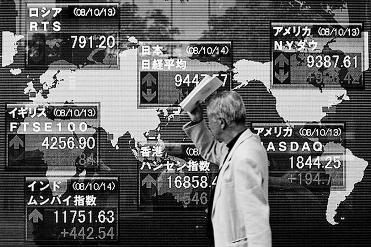 Seorang pejalan kaki melirik ke papan pengumuman yang memperlihatkan pergerakan harga-harga saham di Tokyo, Jepang, Selasa (14/10). Pada hari itu, indeks Nikkei naik 1.171,14 poin atau 14 persen menjadi 9.447,57 poin saat penutupan sesi perdagangan.  