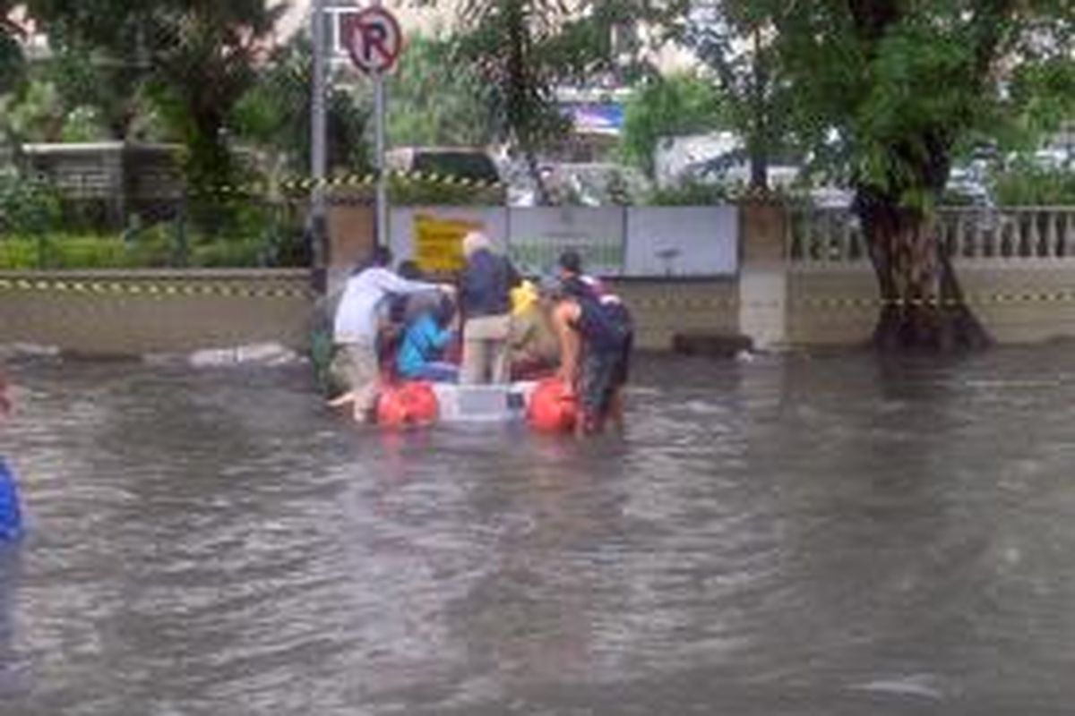 Sejumlah anggota Polisi Pamong Praja membantu warga yang akan melintasi Jalan Tanjung Duren Raya, Rabu (29/1/2014). Banjir setinggi 50-60 sentimeter menggenangi wilayah jalan tersebut.