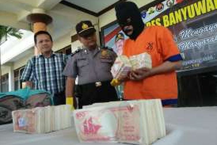 Abah Giman warga Kecamatan Kalibaru yang melakukan penipuan dengan modus penggandaan uang saat diamankan bersama barang bukti uang pecahan seratus rupiah