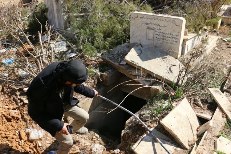 Warga menunjukkan makam warga Kristen Suriah yang sudah terbuka dan berantakan di Harasta.
