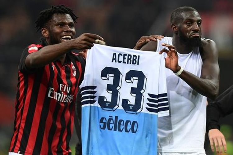 Tiemoue Bakayoko dan Franck Kessie memamerkan kostum milik Francesco Acerbi di hadapan Curva Sud, Senin (15/4/2019)