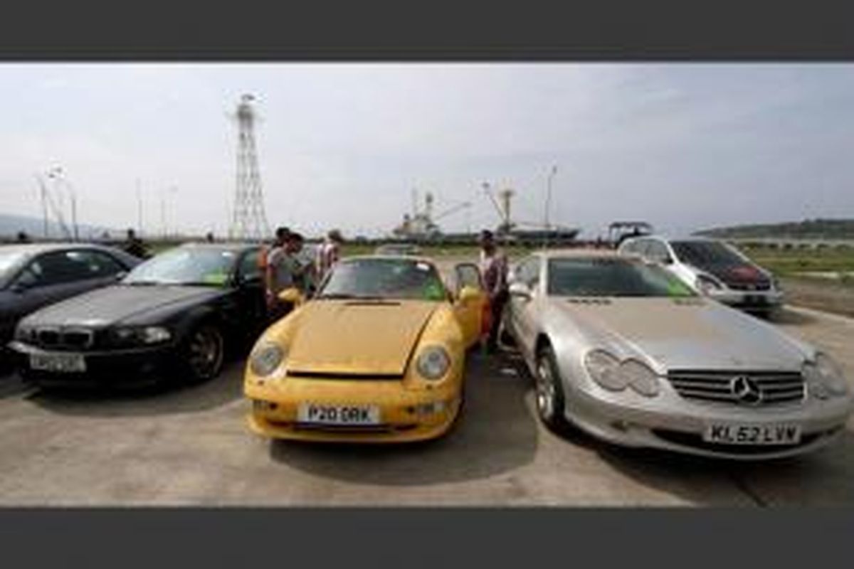 Pekerja menurunkan mobil sport eks Eropa saat tiba di Pelabuhan Malahayati, Krueng Raya, Aceh Besar, 31 Maret 2014. Sebanyak 30 unit mobil bekas 2.500 CC seperti Porsche, BMW, Mercedes Benz dijual dengan harga Rp 150 juta hingga Rp 350 juta.