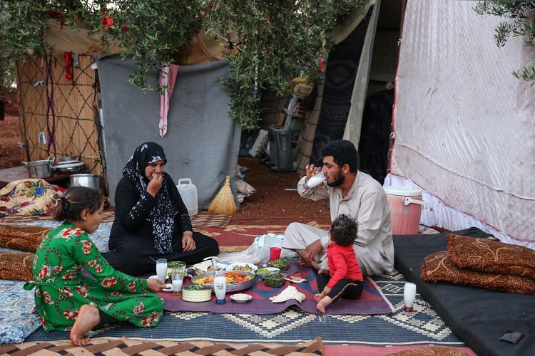 Sebuah keluarga tengah berbuka puasa di lapangan dekat kamp desa Atme, kawasan yang dikuasai ekstremis di Idlib, Suriah, pada 19 Mei 2019.