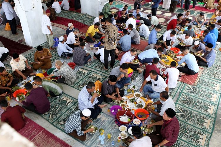 Warga menikmati makanan yang disajikan pada peringatan Maulid Nabi Muhammad SAW di Masjid Jamik Lueng Bata, Banda Aceh, Aceh, Selasa (19/10/2021). Pada setiap perayaan hari kelahiran (maulid) Nabi Muhammad SAW yang berlangsung selama tiga bulan di Aceh, warga selain menyiapkan berbagai makanan dengan menu utama Kuah Beulangong (kari daging sapi atau kambing dengan bumbu khas) untuk dinikmati bersama juga menggelar zikir, menyantuni anak yatim, fakir dan miskin. ANTARA FOTO / Irwansyah Putra/aww.